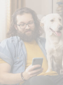 A man relaxing at home with his dog while he contacts ResMed via his mobile phone