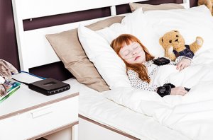 A young girl sleeping with her teddy while connected to the Nox-C1s access point device.