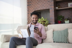 A man on the sofa with a package as he looks at the ResMed online shop on his phone