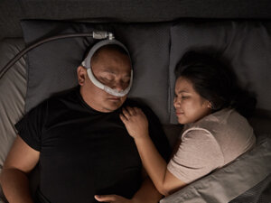 A patient wearing a ResMed AirFit P30i nasal pillows mask.