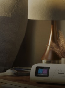 An AirCurve 11 BIPAP device, mask and mobile phone showing the myAir app on a bedside table