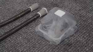 A still from a CPAP cleaning video showing a humidifier tub and tube wrap, overlaid with a play arrow.