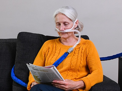 A woman receiving high-flow therapy treatment being assessed by her healthcare professional in a medical office.