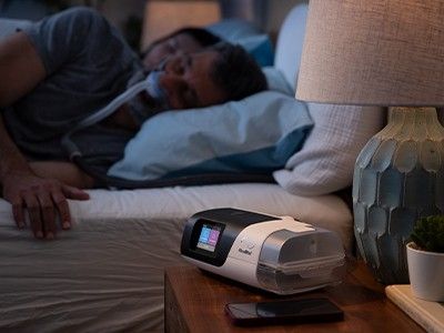 Someone sleeping with their CPAP device beside their bed