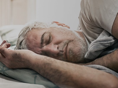 A close-up of a man sleeping soundly on his side, undisturbed by sleep apnoea